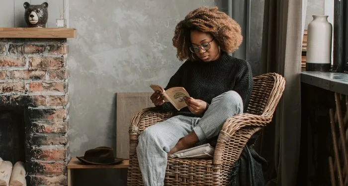 a Black woman reading in an armchair