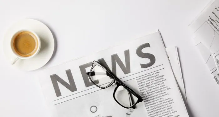eyeglasses, cup of coffee and newspapers, on white table